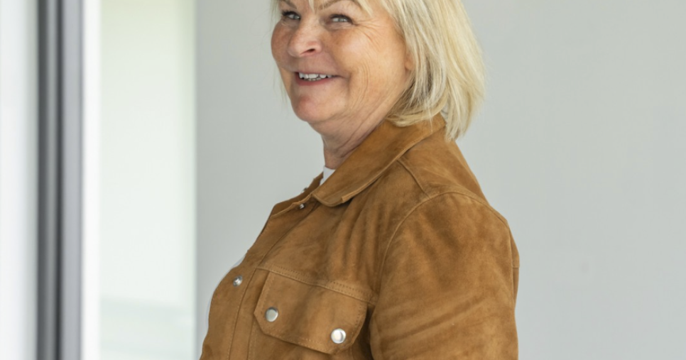 Portrait de Nadine Rapp, décoratrice d'intérieur en Alsace, souriante sur un chantier en cours à Mulhouse, veste camel en daim.