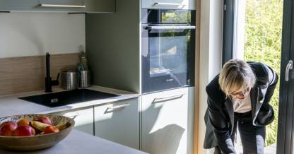 Cuisine sur mesure aux façades vert sauge avec îlot central et ouverture jardin, conçue par Nadine Rapp architecte d'intérieur à Mulhouse