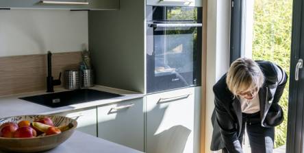 Cuisine sur mesure aux façades vert sauge avec îlot central et ouverture jardin, conçue par Nadine Rapp architecte d'intérieur à Mulhouse